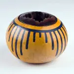 A yellow and black vase sitting on top of a table.